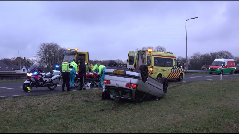 Auto op de kop naast N9, bestuurder gewond