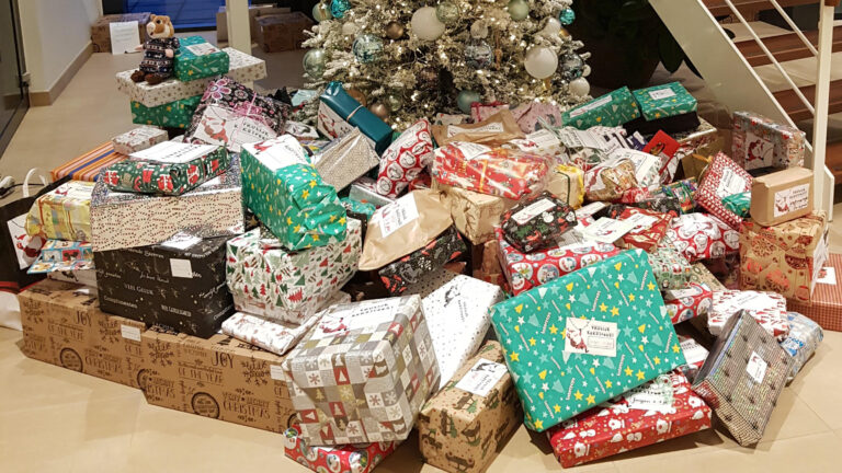 Medewerkers VRNHN en GGDHN geven stapel cadeaus aan kinderen verbonden aan voedselbank