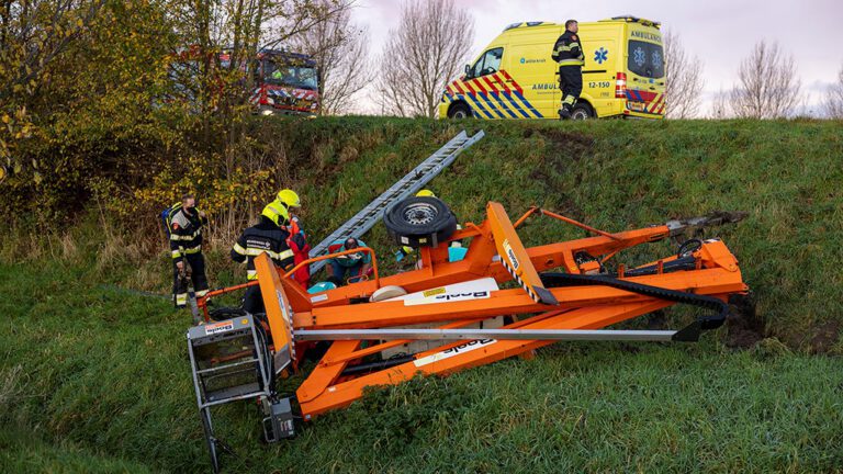 Aanhanger met hoogwerker valt van viaduct en schept fietser