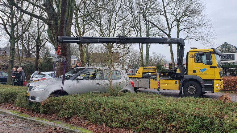 Gas in plaats van rem doet auto op paaltje en in heg belanden