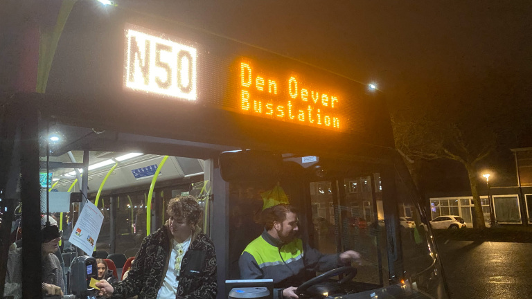 Bus met nummer N50 naar Den Oever Busstation bij nacht, met passagier die incheckt en chauffeur.