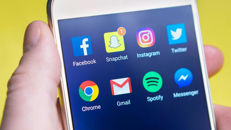 Close-up van een smartphone met applicatie-iconen voor Facebook, Snapchat, Instagram, Twitter, Chrome, Gmail, Spotify en Messenger op het scherm.