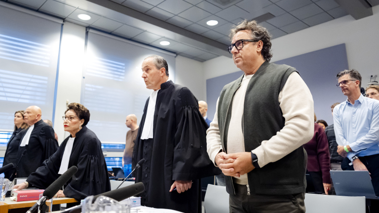 Mensen in een rechtszaal, met twee personen in toga's en andere aanwezigen op de achtergrond.