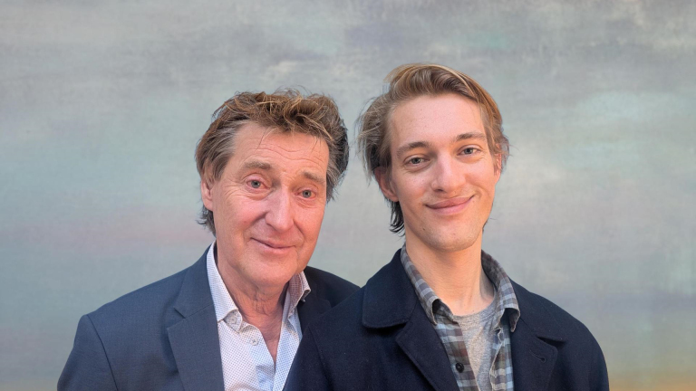 Twee mannen poseren glimlachend voor een neutrale achtergrond.