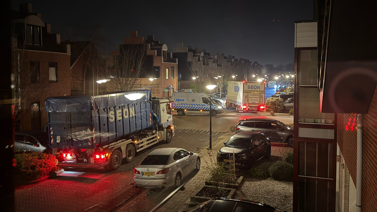 Vrachtwagens en bestelwagens met het logo "SEON" staan in een woonwijk 's nachts, verlicht door straatlantaarns.