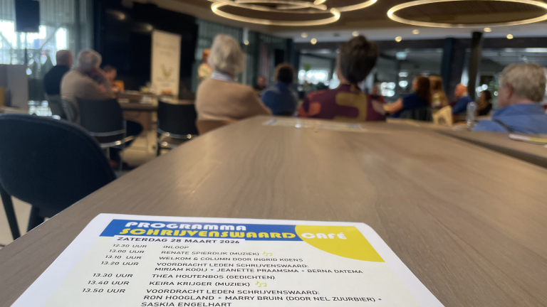 Een programmablad van het Schrijvenswaard Café met mensen zittend in een zaal op de achtergrond.