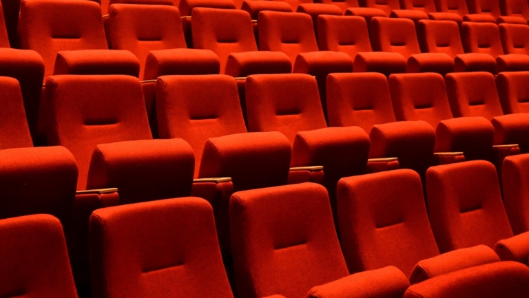 Rijen met lege rode theaterstoelen.