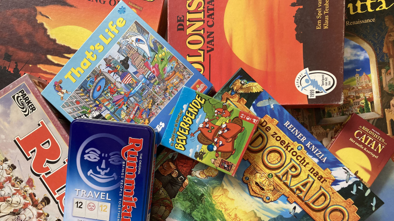 Een verzameling van verschillende bordspeldozen, waaronder "De Kolonisten van Catan", "Rummikub" en "Beverbende".