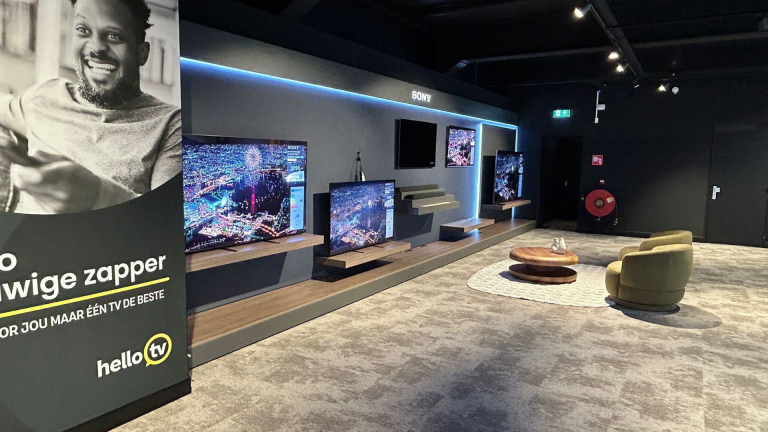 Showroom met Sony-televisies op wandplanken en zithoek; links poster met lachende man en tekst helloTV