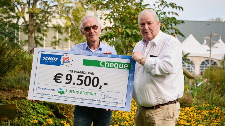 Twee mannen houden een grote cheque van € 9.500 vast voor Hortus Alkmaar, buiten in een tuin