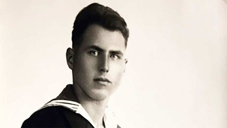 Zwart-witportret van een jonge man met naar achter gekamd haar in marine-uniform, kijkend naar de camera