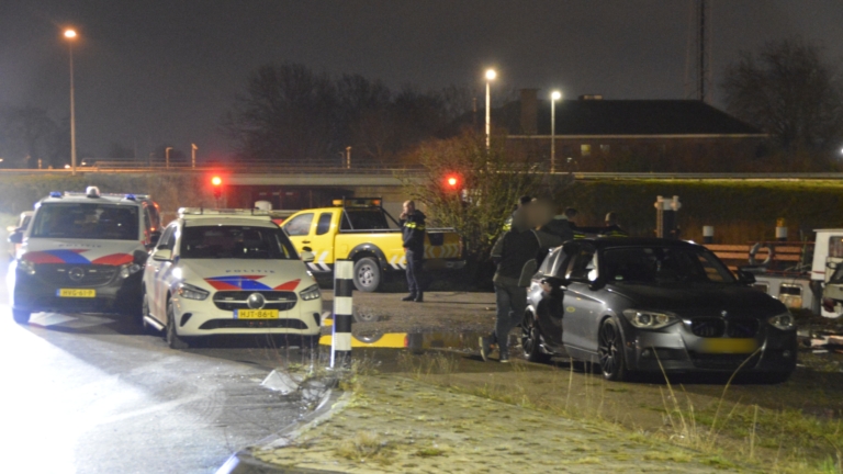 Meerdere politieauto's staan geparkeerd langs een weg in de nacht, met agenten bij een voertuig.