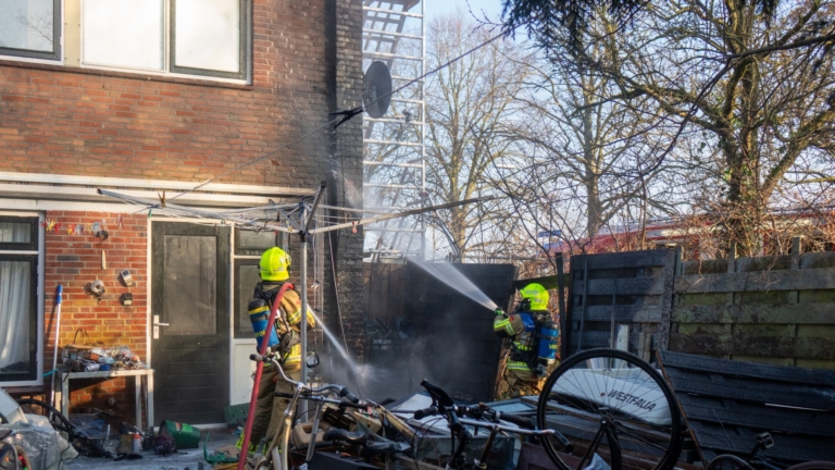 Brandweermannen bestrijden een woningbrand met een brandweerwagen en uitrusting, omgeven door rook.