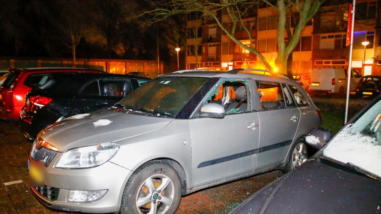 Drie auto's, waarvan één zwaar beschadigd door brand, met een brandweerman op de achtergrond.