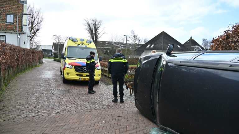 Politieagenten staan bij een geparkeerde auto voor een supermarkt, met een politiewagen op de achtergrond.