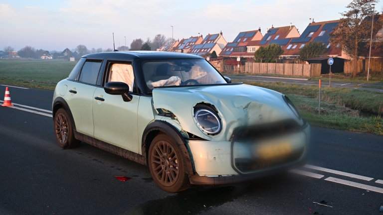 Auto-ongeluk met een ambulance en hulpverleners op de weg, waarbij meerdere auto's en verkeersborden zichtbaar zijn.
