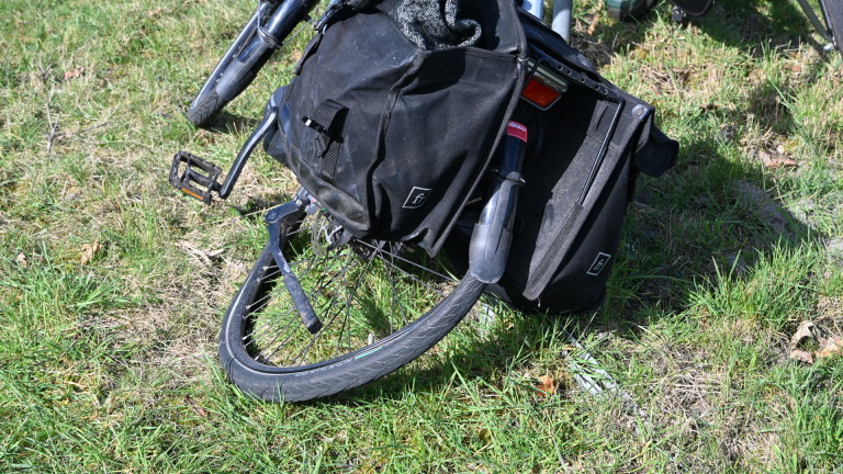 Politiemotor op een fietspad naast een klassieke auto en een fiets, met agenten op de achtergrond in gesprek.