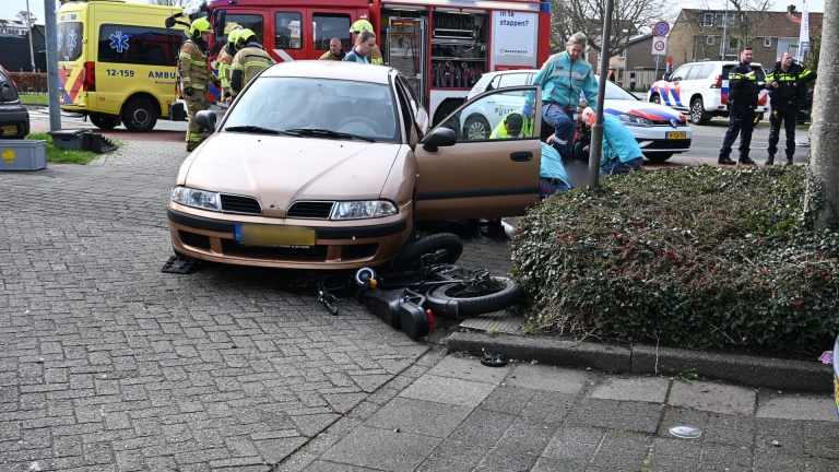 Hulpverleningsvoertuigen en mensen verzamelen zich bij een ongevalslocatie voor een gebouw.