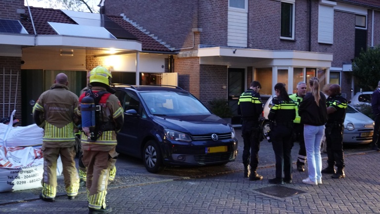 Politiemotor en agent op straat tijdens een avondlijke situatie met publiek en een brandweerwagen op de achtergrond.