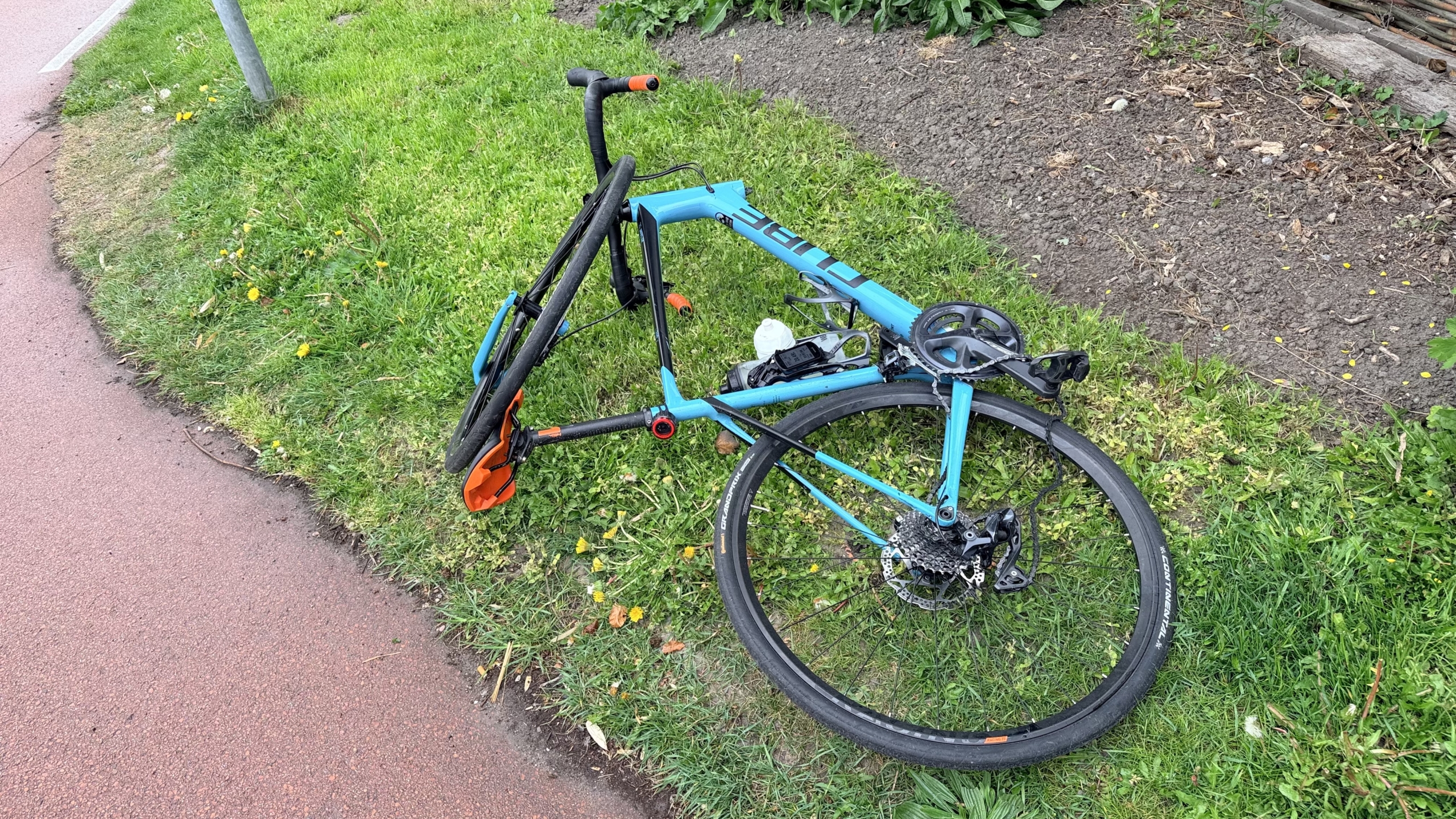 Politieagenten en een ambulance op een kruispunt, met enkele mensen bij een auto betrokken bij een incident.