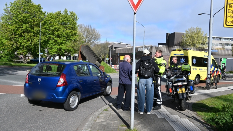 Politieagenten en ambulancepersoneel bij een ongeval; politie motorfiets op de voorgrond, met een geopende ambulance op de achtergrond.