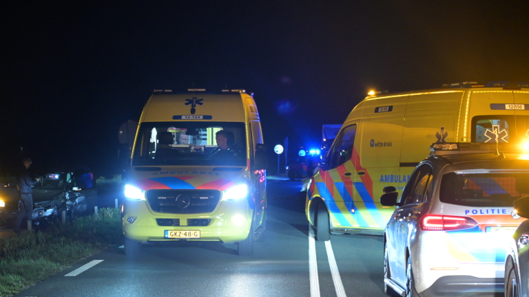 Auto met zware schade aan de voorkant staat op een sleepwagen in het donker.