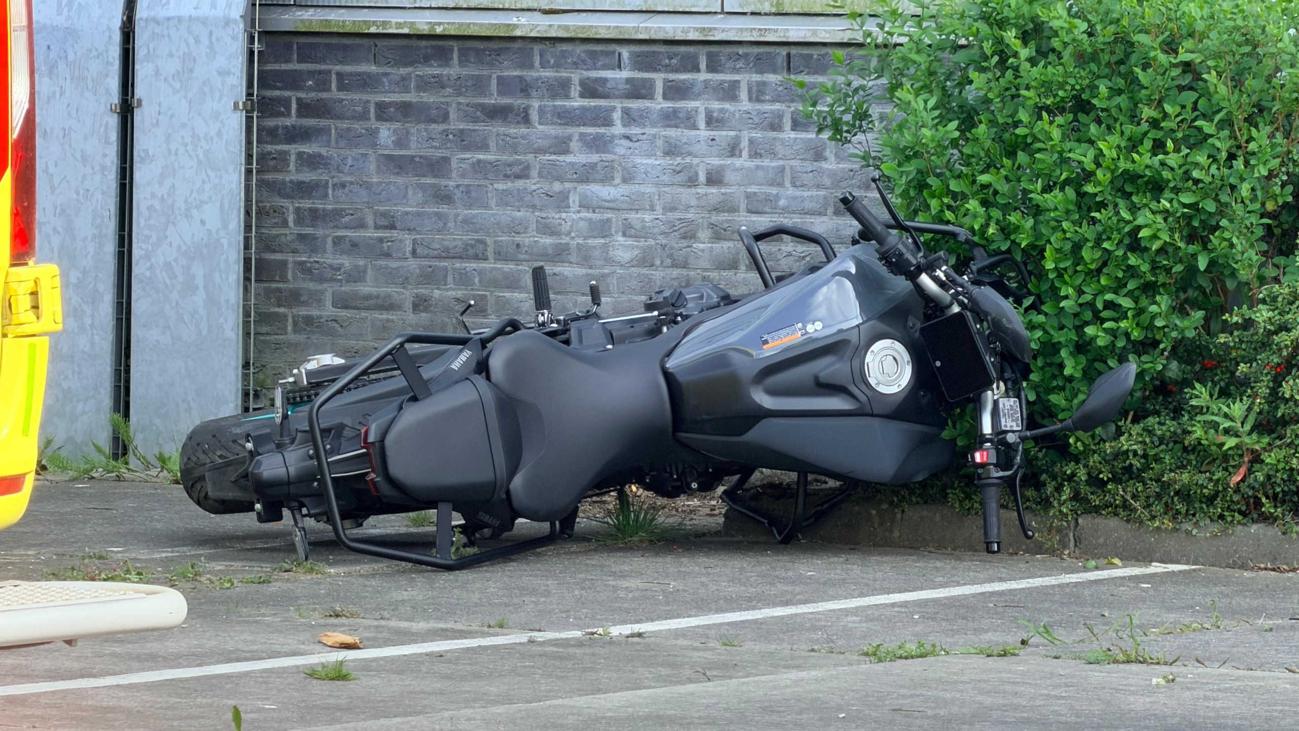 Politie, brandweer en ambulance staan buiten een groot gebouw geparkeerd; agenten en brandweerlieden zijn actief.