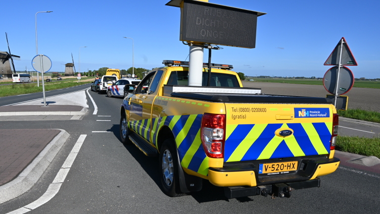 Twee auto's, een groene en een witte, zijn gebotst, met schade aan de achterkant van de groene auto.
