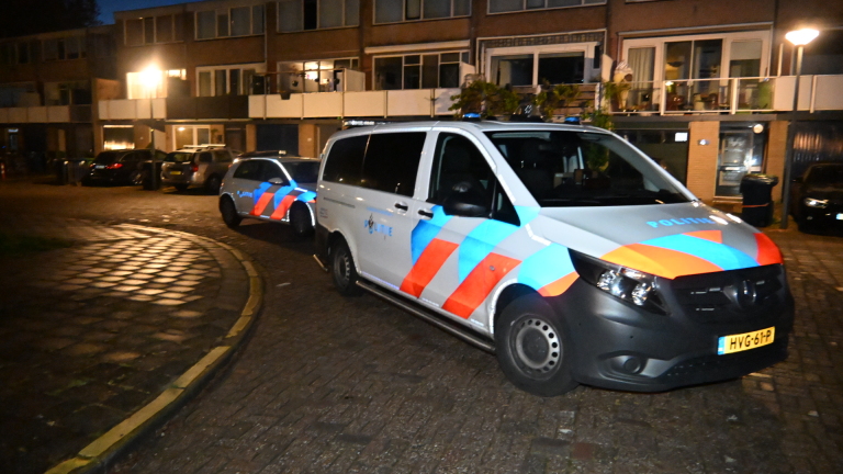Verlichte voordeur van een huis 's nachts, omgeven door planten en afgesloten met politieafzetting.