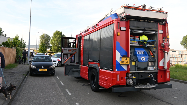 Politie- en ambulancevoertuig staan geparkeerd op straat naast mensen met een brancard, waarschijnlijk bij een noodsituatie.