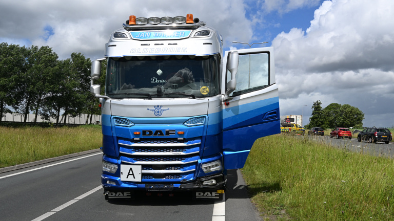 Twee beschadigde auto's en een omgevallen verkeerspaal op de weg, omgeven door mannen in fluorescerende kleding.