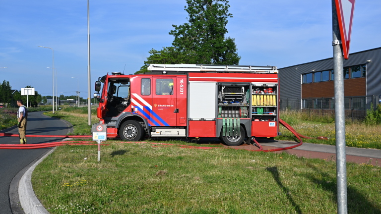 Brandweerlieden in gele helmen en uitrusting staan op een kruispunt, klaar voor actie met brandblussers.