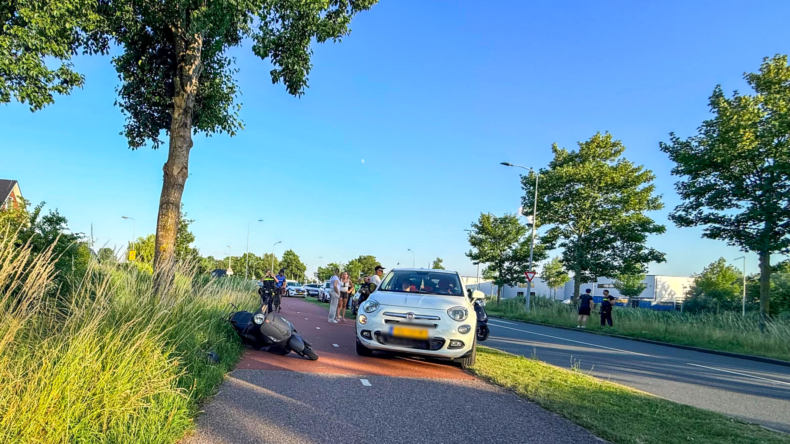 Politie- en handhavingsvoertuigen staan langs de weg, waar agenten met een groep mensen bezig zijn.