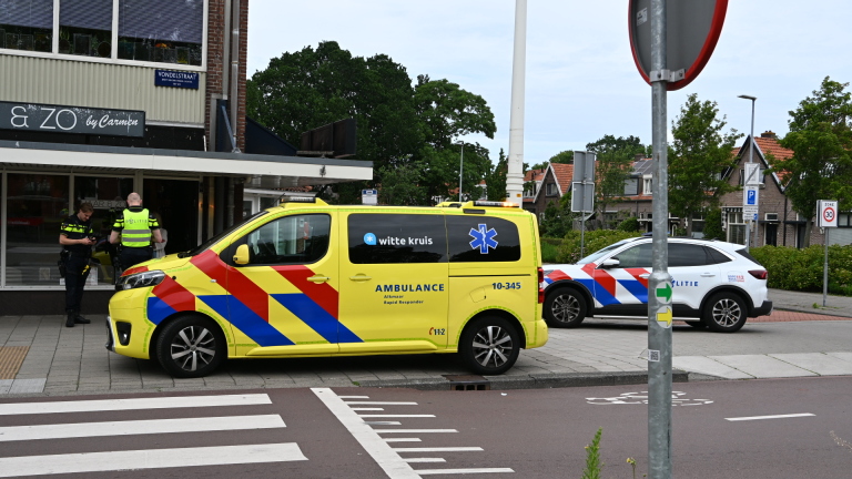 Zwarte elektrische fiets met dikke banden geparkeerd naast een metalen container op een stoep.