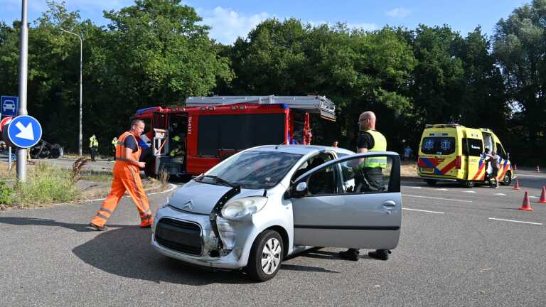Hulpdiensten en politie bij een ongeval op de weg, met een auto die op zijn dak ligt en een brancard ernaast