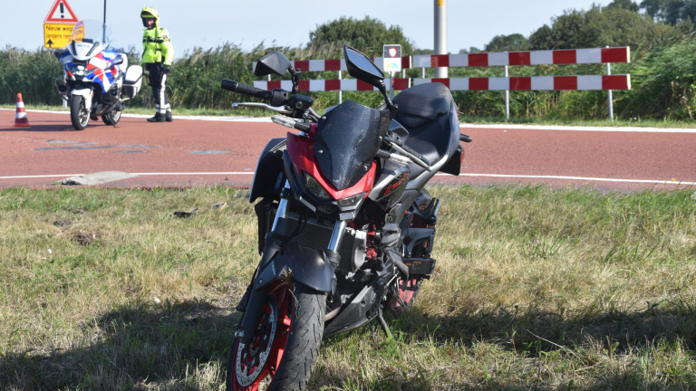 Ambulance en politieauto blokkeren een fietspad langs de weg bij een ongeval, met hulpverleners op de achtergrond