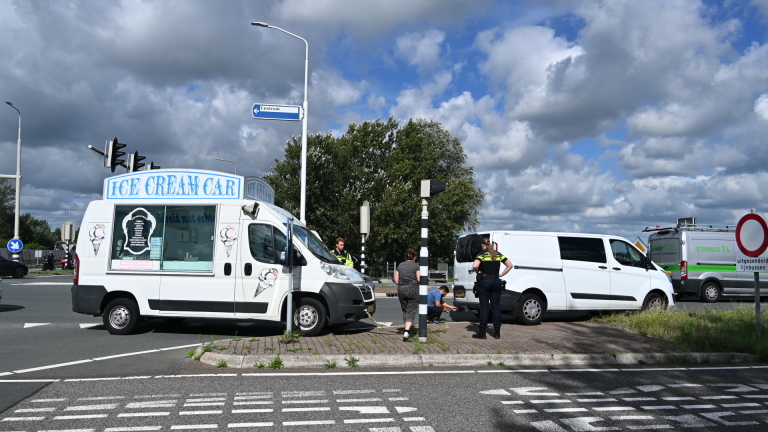 IJswagen met bord Ice Cream Car staat stil bij kruispunt, naast een witte bestelbus en politie op de weg