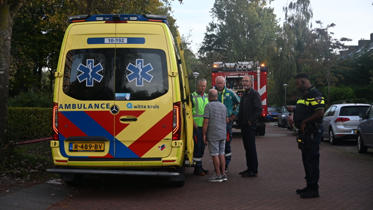 Brandweerman en medewerker inspecteren een door brand beschadigd balkon met roetsporen en kapotte ramen