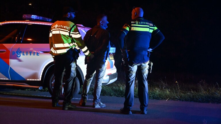 Politiecontrole ’s nachts met politiebusje met zwaailichten, agenten en kegels langs de weg