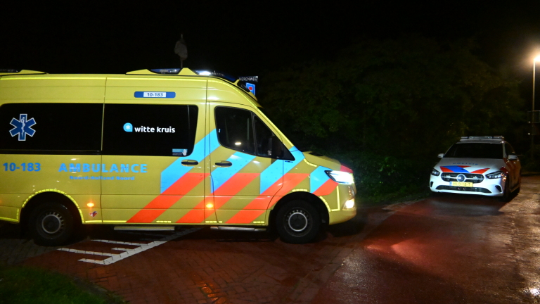 Afgezette ongevalslocatie met beschadigde auto en omgevallen fiets in het gras, met hulpverleners in de achtergrond