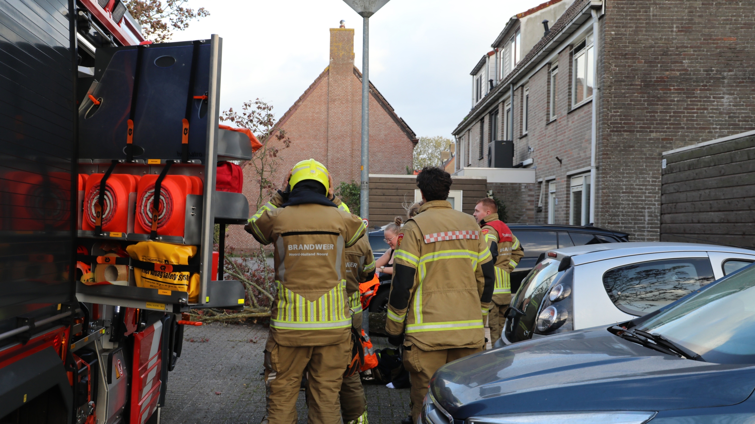 Handhaver staat bij met lint afgezet parkeerterrein waar een omgevallen boomtak op auto’s is gevallen